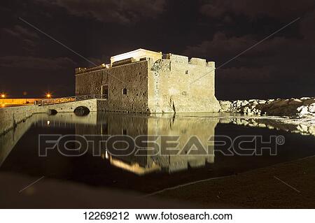 Stock Image - An old ruined medieval castle reflected in tranquil water at nighttime; Paphos, Cyprus. Fotosearch