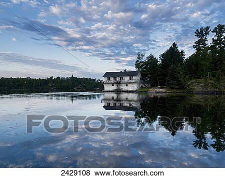 An old worn white house sits on the shoreline of a tranquil lake reflecting clouds in the sky; Ottawa, Ontario, Canada View Large Photo Image Stock Photo - An old worn white house sits on the shoreline of a tranquil lake reflecting clouds in the sky; Ottawa, Ontario, Canada. Fotosearch