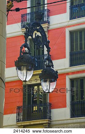 An ornate metal light fixture hanging in front of a red residential building; Barcelona, Spain View Large Photo Image Stock Photography - An ornate metal light fixture hanging in front of a red residential building; Barcelona, Spain. Fotosearch