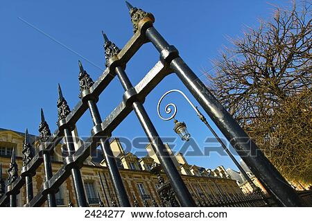 Stock Photo - An ornate metal railing by a building and blue sky, Marais district; Paris, France. Fotosearch