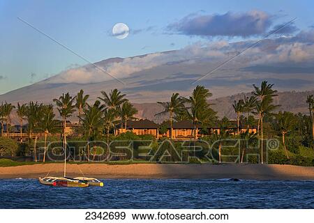 Stock Photo - An outrigger canoe in Kukio Bay with a view of Mauna Kea in the distance; Big Island, Hawaii, United States of America. Fotosearch
