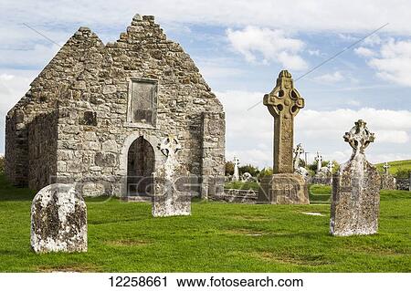 Stock Image - Ancient stone roofless church with celtic crosses in a grassy field; County Offaly, Ireland. Fotosearch