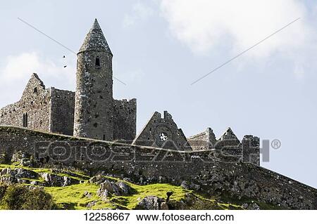 Ancient stone ruin with stone wall, turret and church on rocky grassy hillside with blue sky and clouds; Cashel, County Tipperary, Ireland View Large Photo Image Stock Photo - Ancient stone ruin with stone wall, turret and church on rocky grassy hillside with blue sky and clouds; Cashel, County Tipperary, Ireland. Fotosearch