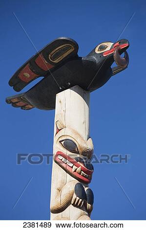 Stock Photo - Animals carved and painted on a wooden totem pole against a blue sky; Whitehorse, Yukon, Canada. Fotosearch