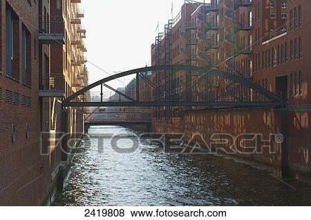 Stock Photo - Arched bridge over a canal between buildings; Hamberg, Germany. Fotosearch