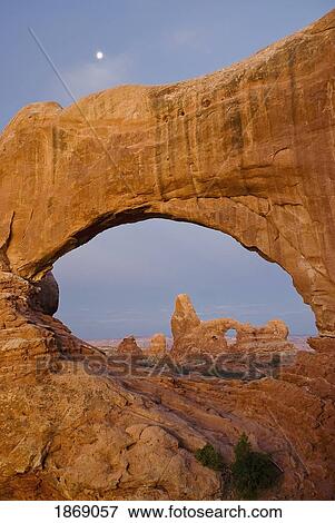 Arches National Park, Utah, United States Of America; Turret Arch Seen Through The North Window At Sunrise With A Full Moon Above View Large Photo Image Stock Photo - Arches National Park, Utah, United States Of America; Turret Arch Seen Through The North Window At Sunrise With A Full Moon Above. Fotosearch