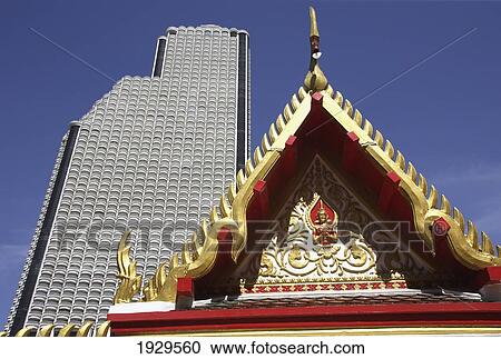 Stock Image - Architecture contrasts of huge high rise building and temple detail from unnamed wat in Bangkok, Thailand.. Fotosearch
