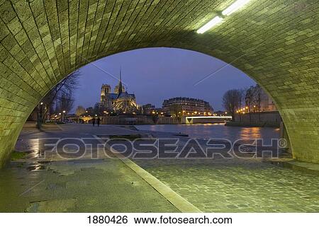 Archway Under Bridge Looking Towards Notre Dame Cathedral At Dusk. View Large Photo Image Stock Photograph - Archway Under Bridge Looking Towards Notre Dame Cathedral At Dusk.. Fotosearch
