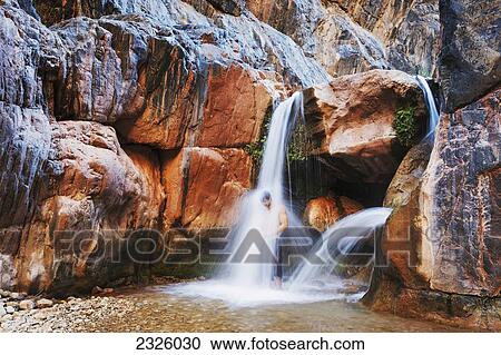 Stock Image - Arizona, Grand Canyon National Park, Clear Creek Falls, Man Under Waterfall.. Fotosearch
