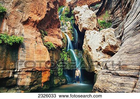 Stock Image - Arizona, Grand Canyon National Park, Young Man Standing In The Waterfall At Elves Chasim.. Fotosearch