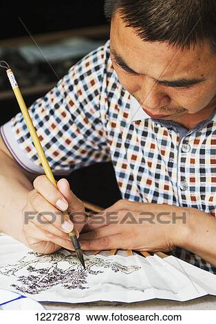 Stock Photo - Artist painting a fan with a traditional Chinese brush, Xidi, Anhui, China. Fotosearch