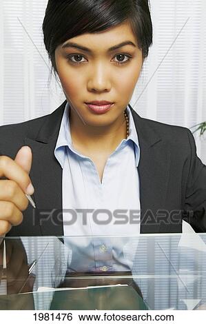 Asian Businesswoman Sitting At Her Office Desk. View Large Photo Image Stock Photograph - Asian Businesswoman Sitting At Her Office Desk.. Fotosearch
