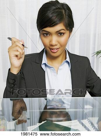 Asian Businesswoman Sitting At Her Office Desk. View Large Photo Image Stock Photography - Asian Businesswoman Sitting At Her Office Desk.. Fotosearch