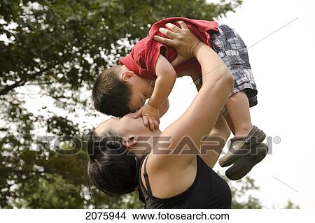 Asian-Caucasian Mother Kissing Her Son And Lifting Him In The Air; Ontario Canada View Large Photo Image Picture - Asian-Caucasian Mother Kissing Her Son And Lifting Him In The Air; Ontario Canada. Fotosearch