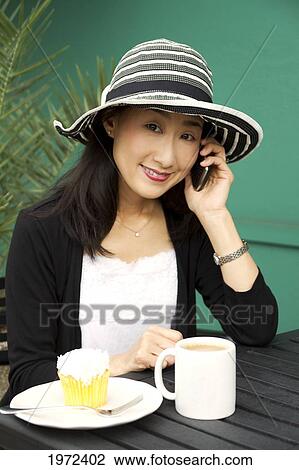 Asian Woman Enjoys A Dessert And Coffee While Chatting On The Phone. View Large Photo Image Stock Image - Asian Woman Enjoys A Dessert And Coffee While Chatting On The Phone.. Fotosearch
