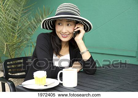 Asian Woman Enjoys Chatting On The Phone At Outdoor Cafe. View Large Photo Image Stock Photography - Asian Woman Enjoys Chatting On The Phone At Outdoor Cafe.. Fotosearch