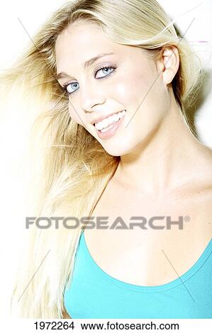 Picture - Attractive Blonde Woman Wearing A Blue Shirt Smiles And Poses In Studio.. Fotosearch