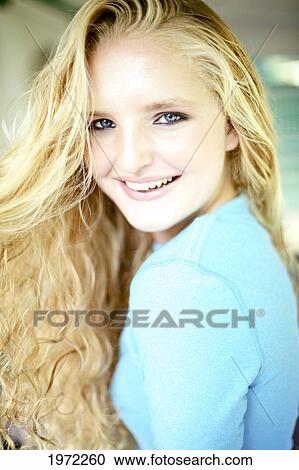Stock Image - Attractive Woman With Long Curly Blonde Hair Poses Outside.. Fotosearch