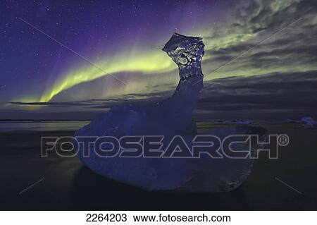 Stock Image - Aurora borealis dances over iceberg from the glacial lagoon jokulsarlon; iceland. Fotosearch