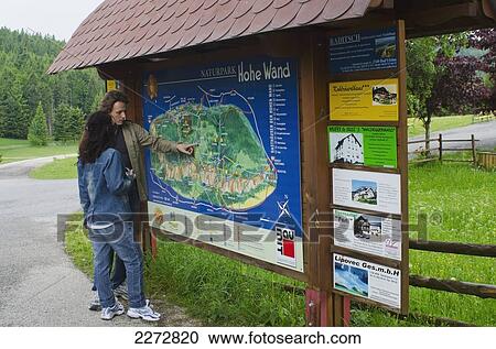Stock Image - Austria, Tourists looking at map of Hohe Wand Naturpark; Hohe Wand. Fotosearch