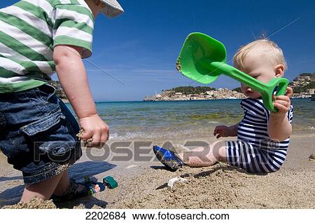 Picture - Baby and young child playing on beach; Majorca, Spain. Fotosearch