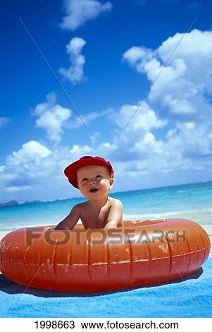 Baby Boy Sits In Beach Tube With Red Cap Blue Skies B1007 View Large Photo Image Stock Image - Baby Boy Sits In Beach Tube With Red Cap Blue Skies B1007. Fotosearch