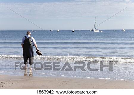Stock Image - Backpacker On Beach, Low Newton By The Sea, Northumberland, England. Fotosearch