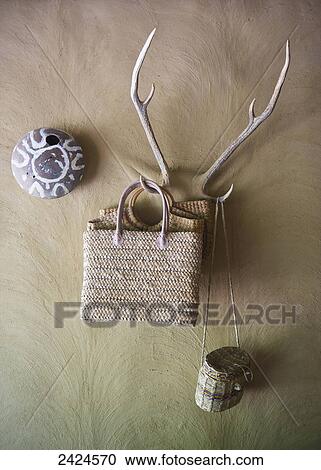 Stock Image - Bags and purse hanging from antler hooks on the wall; Ulpotha, Embogama, Sri Lanka. Fotosearch