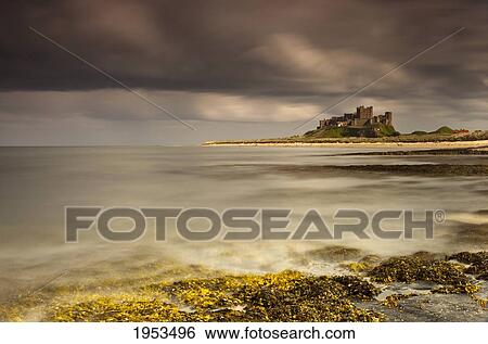 Stock Photograph - Bamburgh Castle Under A Cloudy Sky; Bamburgh Northumberland England. Fotosearch