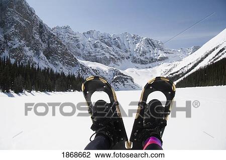 Stock Image - Banff National Park, Alberta, Canada; A Pair Of Snowshoes With A Snow-Covered Taylor Lake. Fotosearch