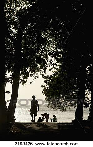 Stock Photograph - Barbados, Silhouette of rasta with beer walking down path to beach late in the afternoon; Paynes Bay. Fotosearch