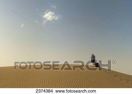 Barefoot man with suitcase on sand dune; Dubai, United Arab Emirates View Large Photo Image Picture - Barefoot man with suitcase on sand dune; Dubai, United Arab Emirates. Fotosearch