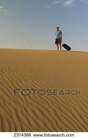 Barefoot man with suitcase on sand dune; Dubai, United Arab Emirates View Large Photo Image Stock Photo - Barefoot man with suitcase on sand dune; Dubai, United Arab Emirates. Fotosearch