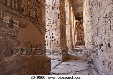 Stock Image - Bas-Reliefs With Original Colors On The Walls And Columns Of A Portico Of The First Courtyard Of The Mortuary Temple Of Ramses Iii, Medinat Habu, Luxor, Qina, Egypt. Fotosearch