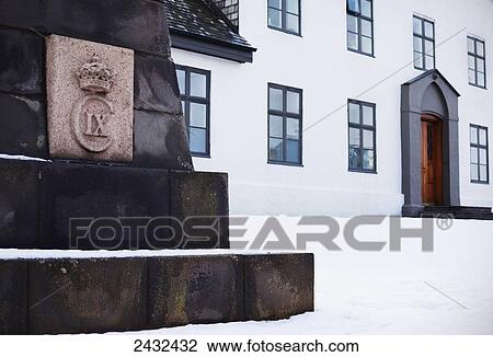 Stock Image - Base of a monument beside a white building with snow; Reykjavik, Iceland. Fotosearch