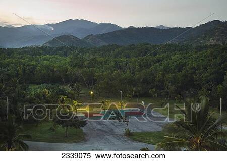 Stock Photography - Basketball Court Illuminated With Lights At Dusk With Mountains In The Background; Santiago Province, Cuba. Fotosearch
