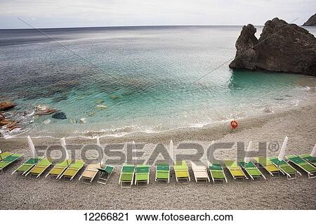 Beach chairs along the water's edge and a view of the horizon; Monterosso Al Mare, Liguria, Italy View Large Photo Image Stock Image - Beach chairs along the water's edge and a view of the horizon; Monterosso Al Mare, Liguria, Italy. Fotosearch