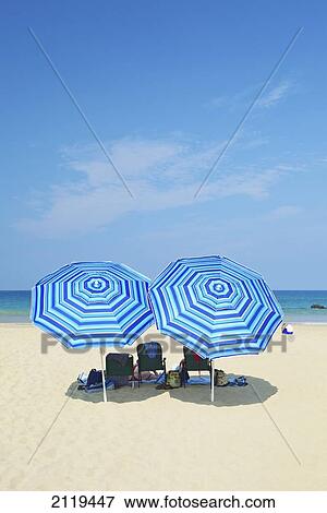 Stock Photo - Beach chairs and blue umbrellas on the beach; Wailua, Hawaii, United States of America. Fotosearch