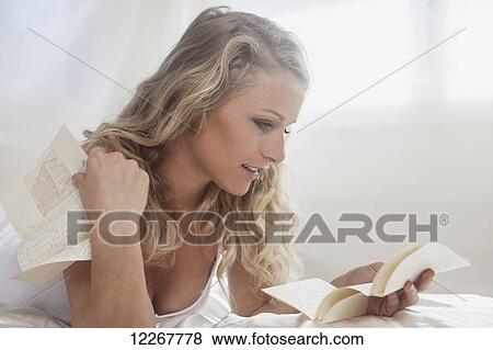 Stock Photo - Beautiful blond woman in her bedroom reading a letter; Kailua, Island of Hawaii, Hawaii, United States of America. Fotosearch