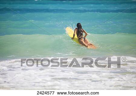 Stock Photo - Beautiful brunette in bikini surfing at Kailua Beach; Kailua, Hawaii, United States of America. Fotosearch