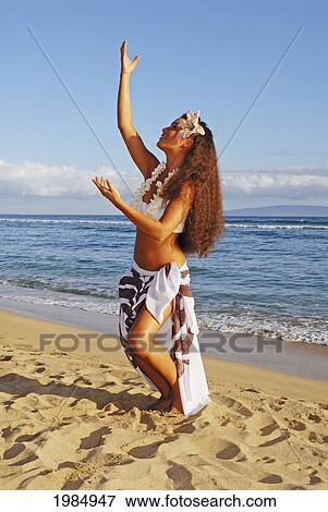 Stock Photo - Beautiful Hawaiian girl dancing hula on ocean shoreline. Fotosearch