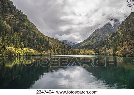 Picture - Beautiful Landscape Of Jiuzhaigou Valley With Forests, Lake, And Mountains Under A Cloudy Sky; Jiuzhaigou, Sichuan, China. Fotosearch