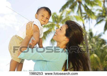 Beautiful Local Mother Holding Little Boy Up In The Air At The Beach, Palm Tree In Background. View Large Photo Image Stock Image - Beautiful Local Mother Holding Little Boy Up In The Air At The Beach, Palm Tree In Background.. Fotosearch