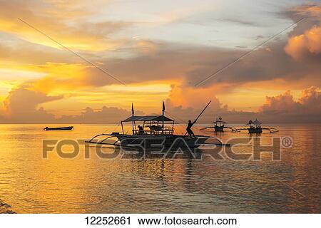 Beautiful sunrise in Alona Beach, a man moving his boat to reach the shore with a long stick; Panglao Island, Bohol, Philippines View Large Photo Image Stock Image - Beautiful sunrise in Alona Beach, a man moving his boat to reach the shore with a long stick; Panglao Island, Bohol, Philippines. Fotosearch