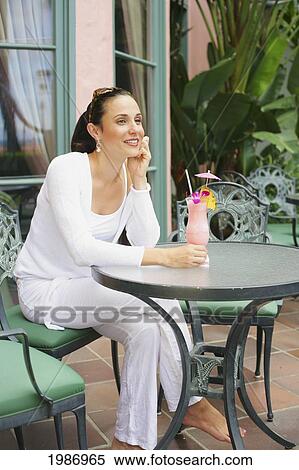 Beautiful Young Woman Sits At An Outdoor Table With A Tropical Cocktail View Large Photo Image Stock Photography - Beautiful Young Woman Sits At An Outdoor Table With A Tropical Cocktail. Fotosearch