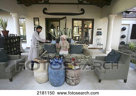Stock Image - Being served tea in the lobby, Baghvan Wilderness Lodge, Pench National Park; Madhya Pradesh, India. Fotosearch