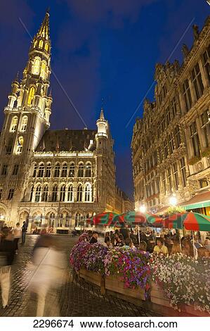 Picture - Belgium, People eating and drinking at cafe tables at dusk in Grand Place; Brussels. Fotosearch