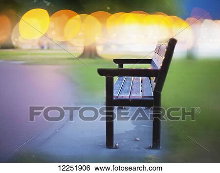 Bench along a path with glowing yellow lights in the distance; Penticton, British Columbia, Canada View Large Photo Image Stock Photograph - Bench along a path with glowing yellow lights in the distance; Penticton, British Columbia, Canada. Fotosearch