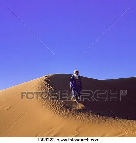 Stock Image - Berber Man Walking In Sand Dunes. Fotosearch