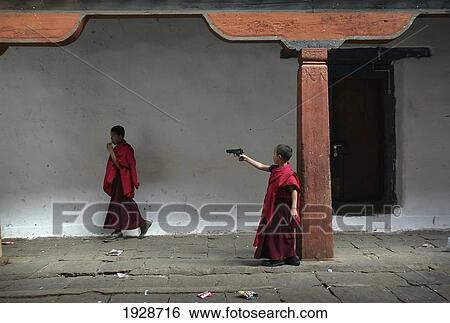 Stock Photograph - Bhutanese Boy Monk Firing A Toy Gun. Fotosearch